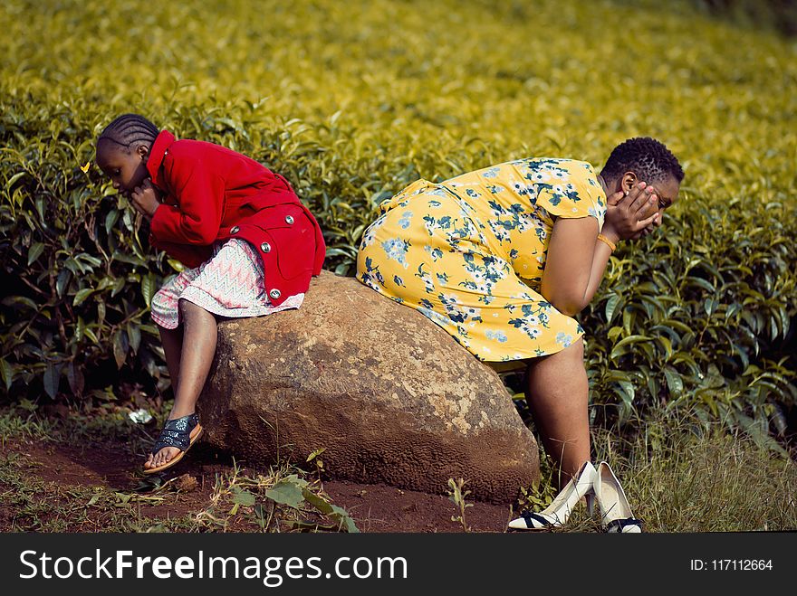 Girl and Woman Sitting on Brown Rock