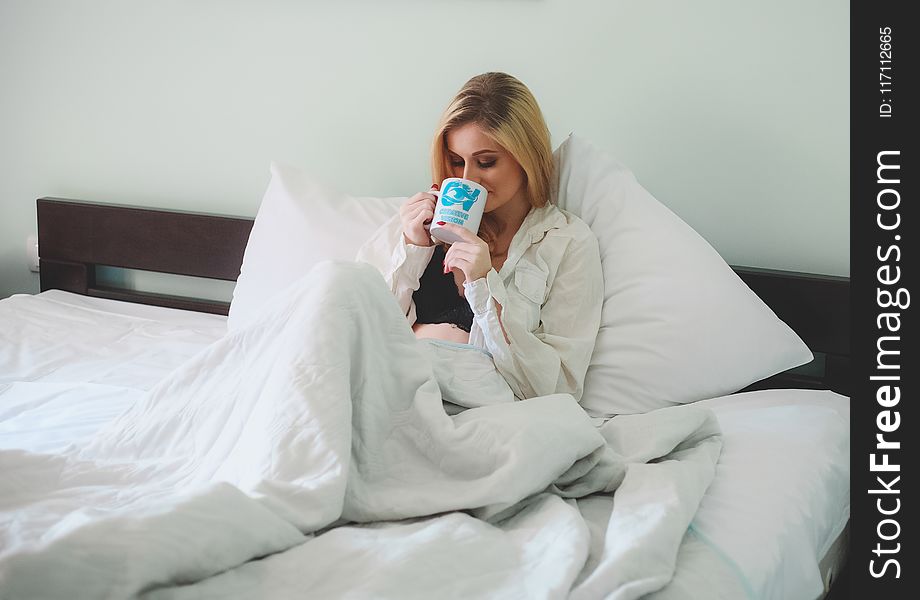 Woman Sitting on Bed Holding Mug