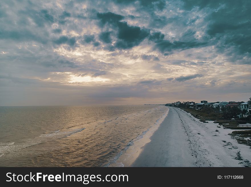 Wide Angle Photo of Shore Under Cloudy Sky