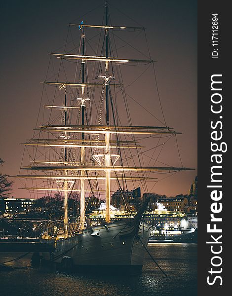 White and Brown Boat With Light Near Buildings at Night