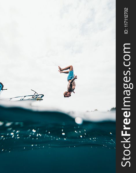 Man Wearing Blue Shorts About to Dive on Body of Water