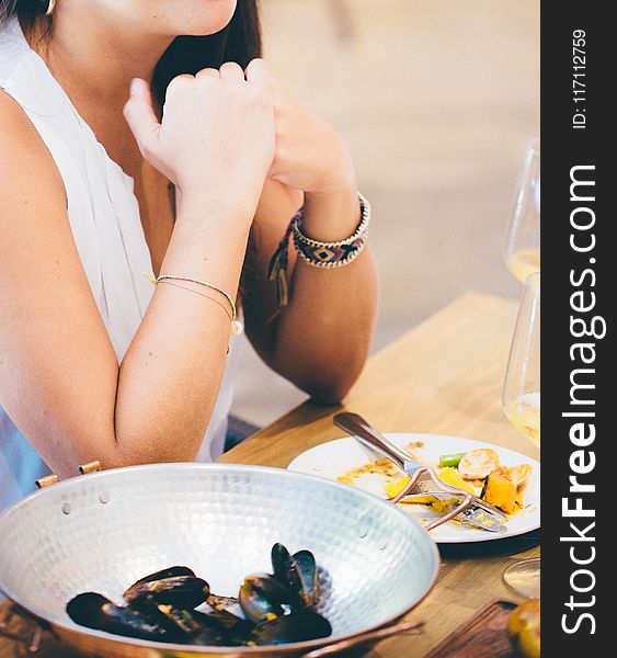 Woman Wearing White Deep V-neck Sleeveless Top Sitting On Chair Near Table