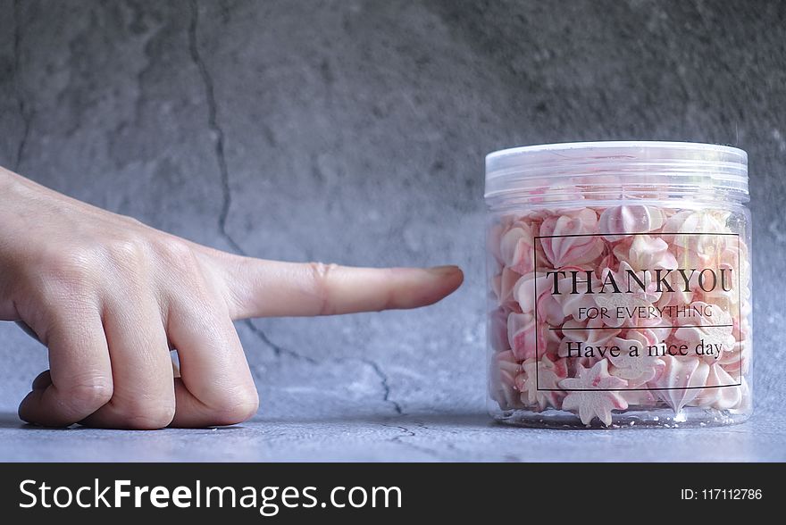 Right Person&#x27;s Index Finger Pointing Clear Plastic Container Filled on Gray Surface