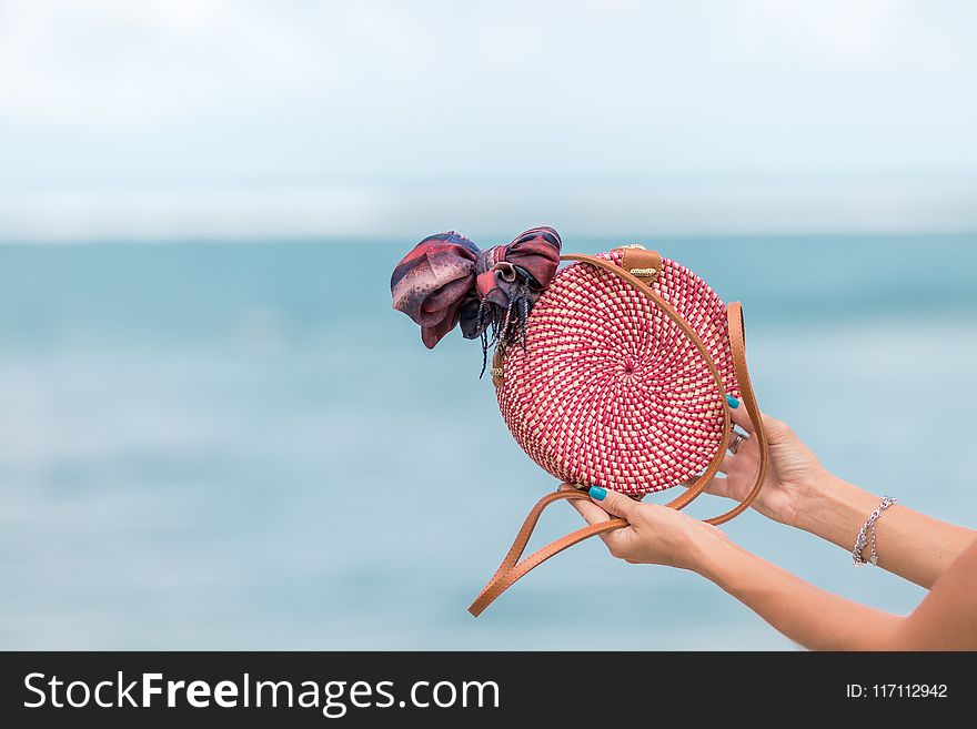 Selective Focus Photography of Person Holding Red and Brown Leather Crossbody Bag