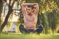 Healthy Lifestyle Concept. Shirtless Young Man Stretching Hands While Sitting In Lotus Pose On A Green Grass. Stock Photo