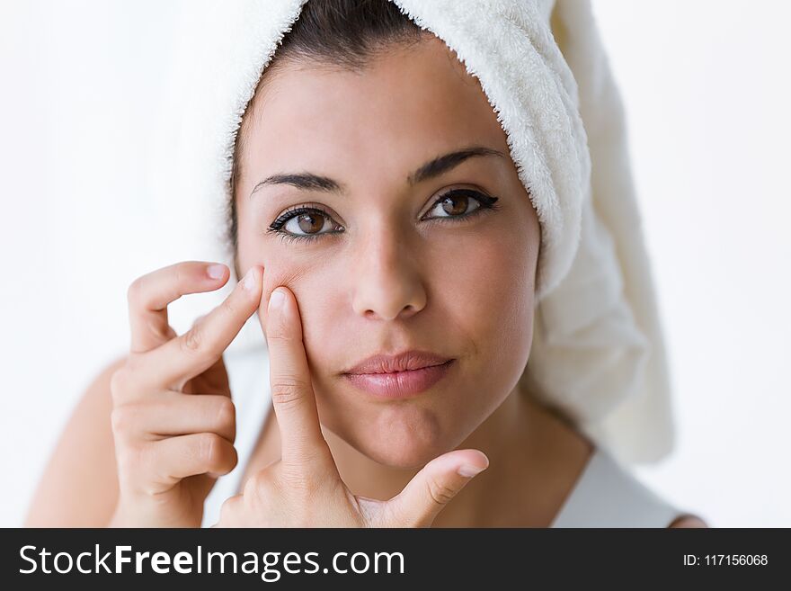 Beautiful young woman removing pimple from her face in a bathroom home.