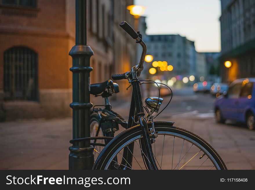 Bicycle in retro style fastened to a post in the dark on a street in a European city.