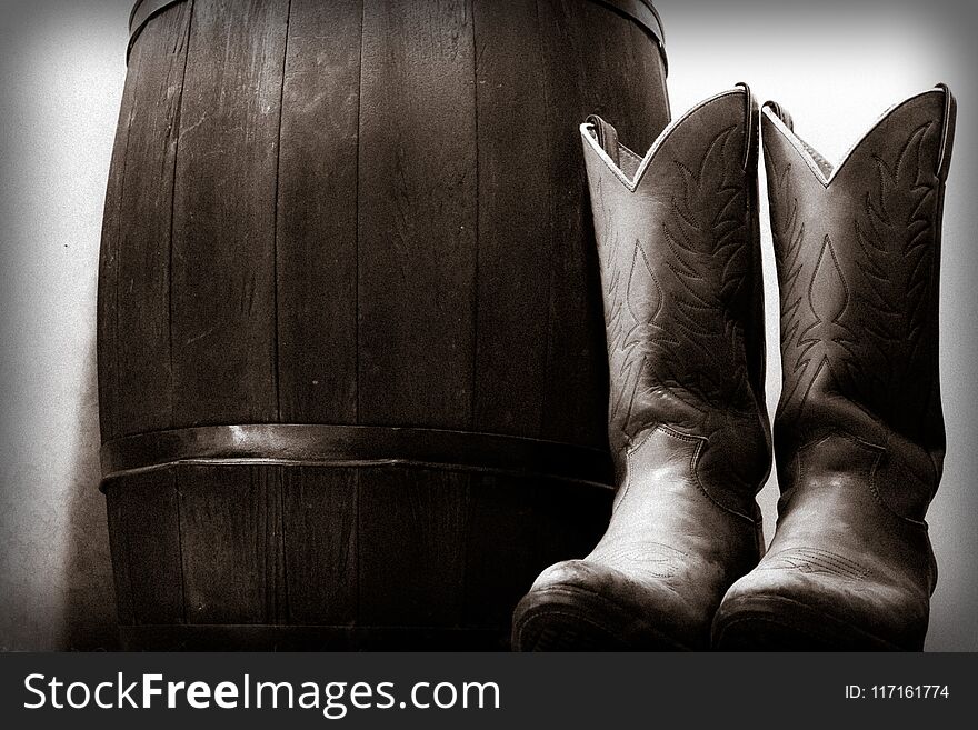 Western cowboy boot next to wooden barrel country old west. Western cowboy boot next to wooden barrel country old west