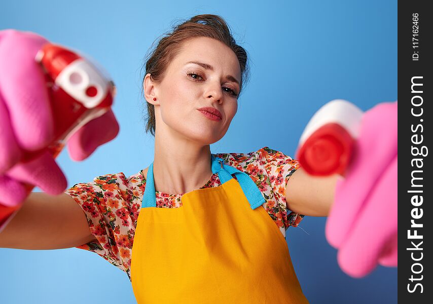 Big cleaning time. cool young housewife with rubber gloves using bottles of cleaning detergent as guns isolated on blue. Big cleaning time. cool young housewife with rubber gloves using bottles of cleaning detergent as guns isolated on blue