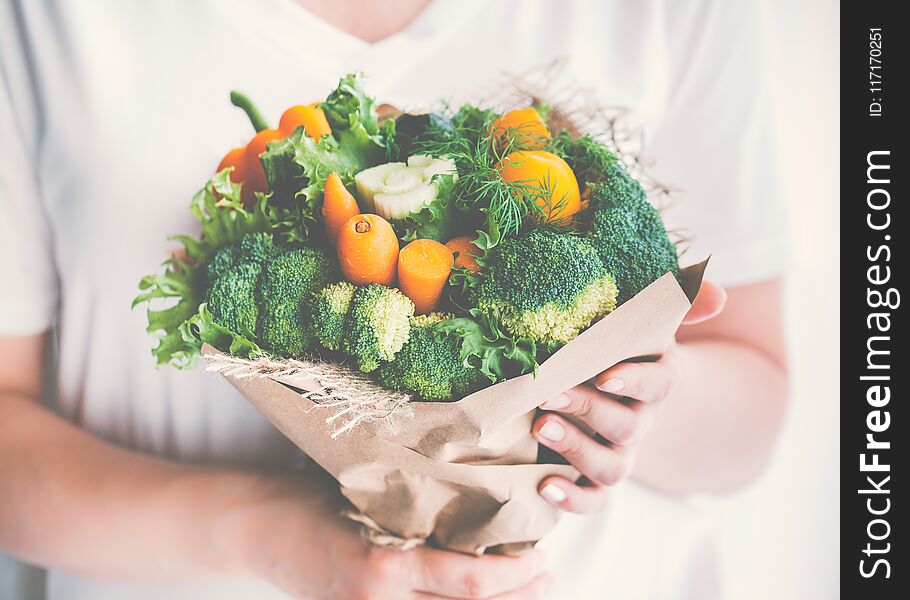 Girl is holding a bouquet of fresh vegetables. Toned image.