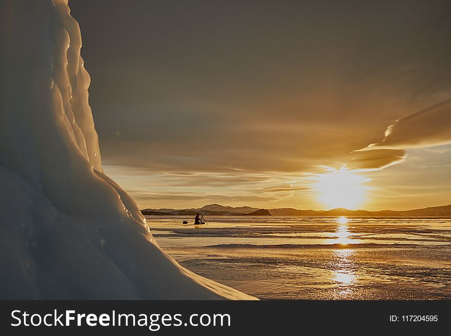 The photographer is shooting a Baikal on the ice, against the backdrop of the setting sun. The photographer is shooting a Baikal on the ice, against the backdrop of the setting sun.