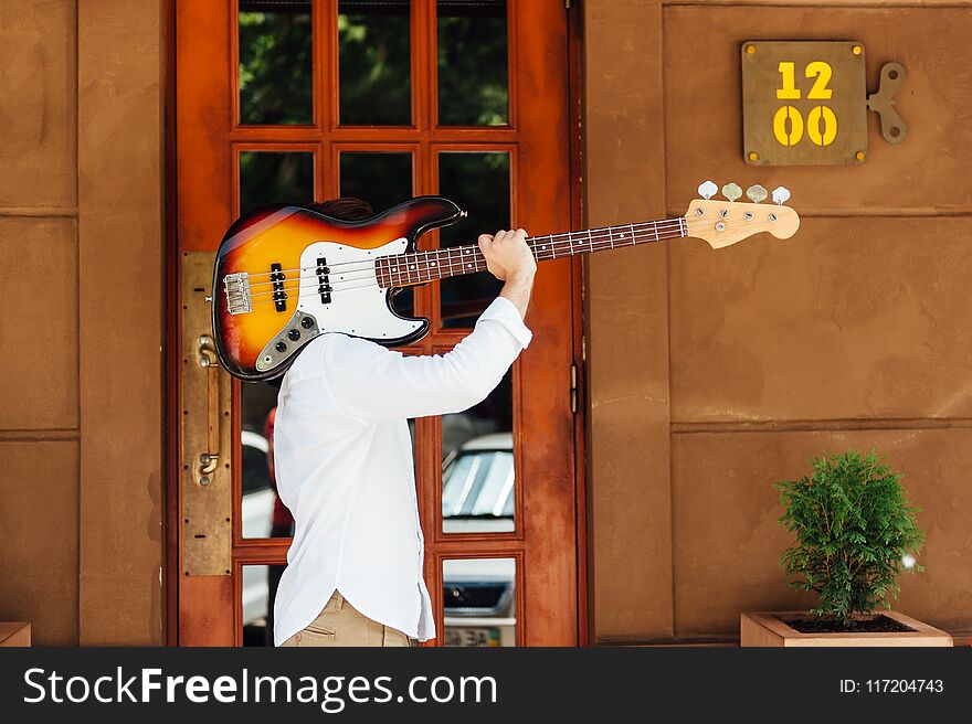 Creative guy guitarist carries a guitar on his shoulder