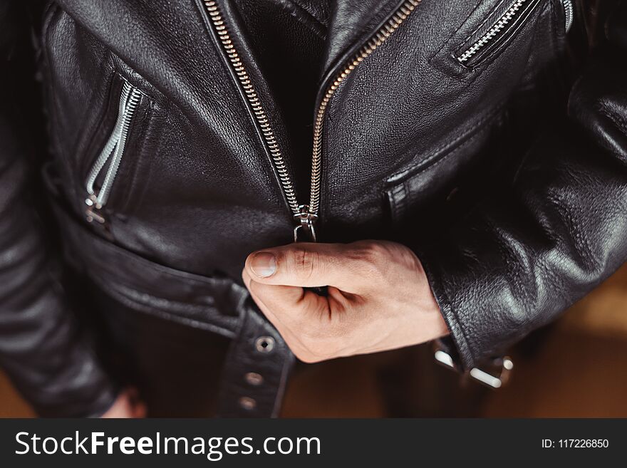 Fastens the lock on a Black leather jacket with zipper close-up. Fastens the lock on a Black leather jacket with zipper close-up