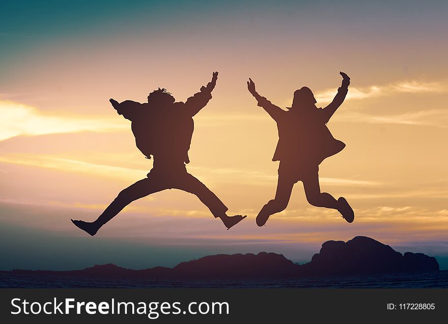 Silhouette young couple a jump on the sea beach at sunset concept of long-awaited vacation. Silhouette young couple a jump on the sea beach at sunset concept of long-awaited vacation