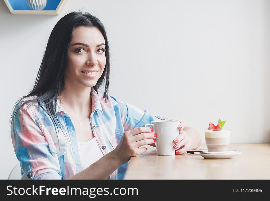 Woman in the cafe with a cup of coffee and strawberry dessert, soft focus background
