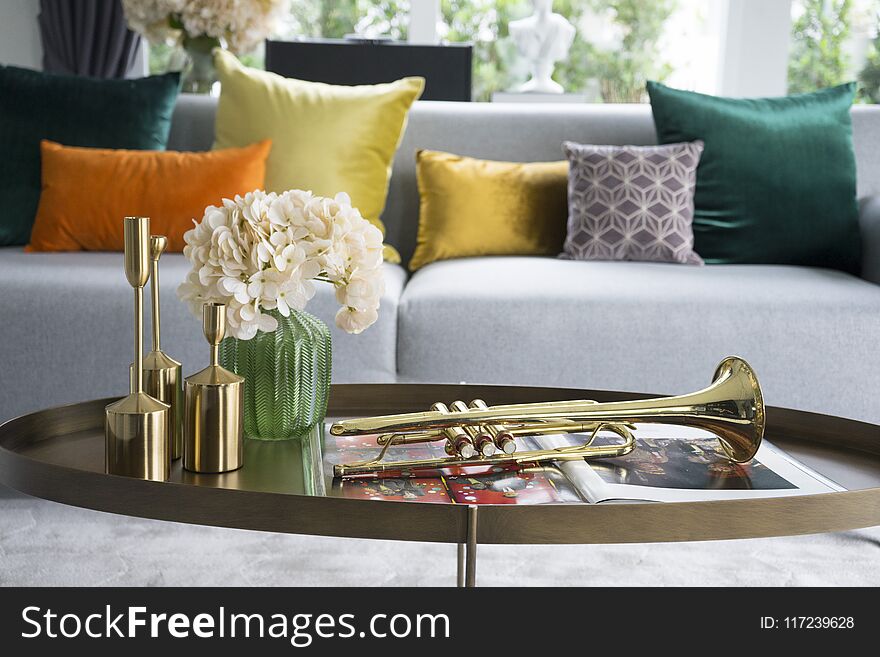 Colorful and stylish living room with flower vase and gold trumpet on table.