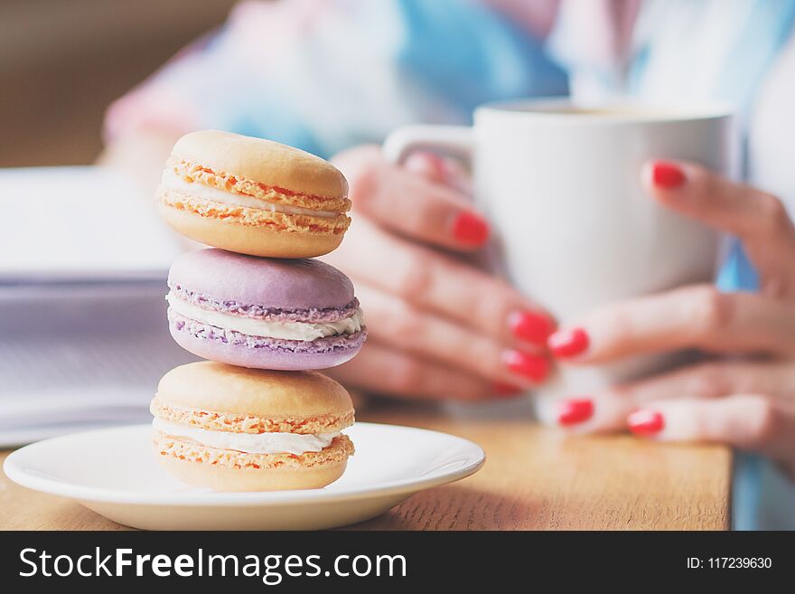 French colored macarons on the plate and a cup of coffee, soft focus background