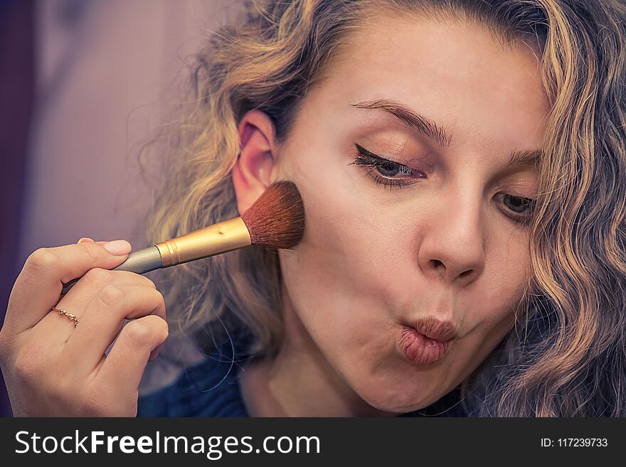 Girl brush makes makeup on the face powder applied to the cheeks. Girl brush makes makeup on the face powder applied to the cheeks