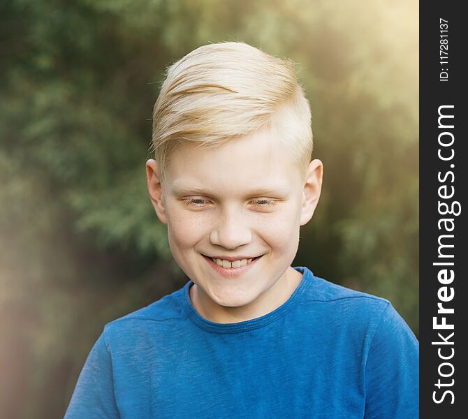 Blond teenager in blue t-shirt smiling. Sincere laughter, a living emotion. Candid boy. Blond teenager in blue t-shirt smiling. Sincere laughter, a living emotion. Candid boy.