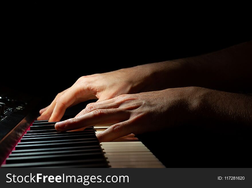 Hands playing a piano keyboard with black background. Hands playing a piano keyboard with black background