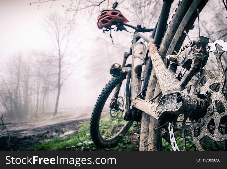 Mountain bike and helmet in autumn woods, dirty bicycle