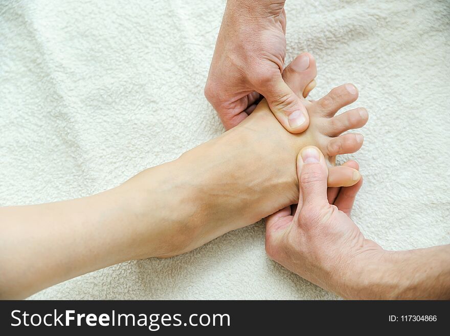 Massage of feet and legs. Male hands are massaging female feet.