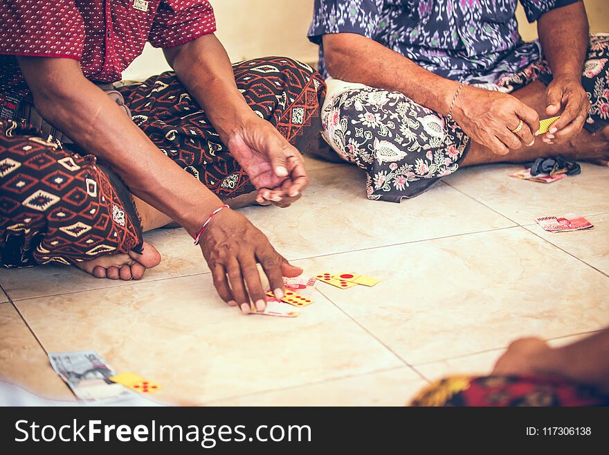 Group Of Balinese Men Playing Cards Sitting On The Floor. Bali Island.