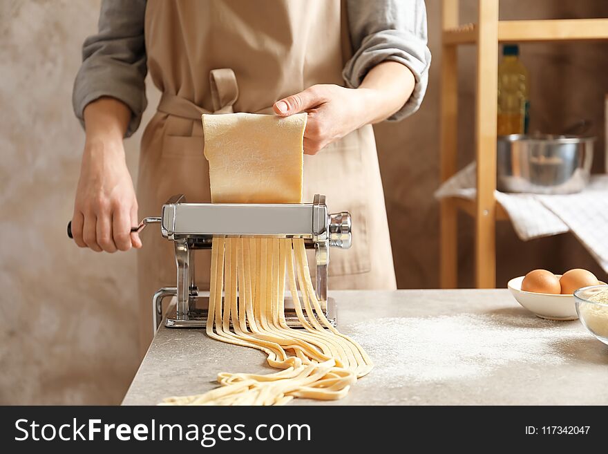 Young woman preparing noodles with pasta maker