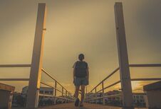 Asian Woman Tourist Walking Alone With Backpack On The Bridge In The City In The Evening On Sunset With Yellow Sky. Walk Away Royalty Free Stock Images