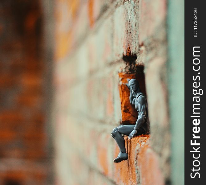 Action Figure On A Hole Of Brick Wall