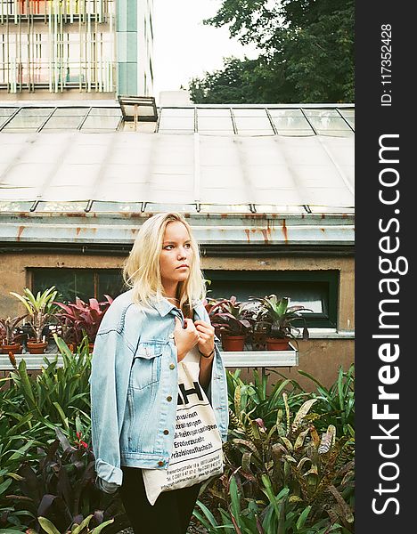 Woman Wearing White Shirt And Denim Jacket Standing Near House