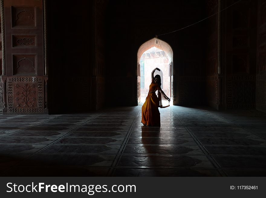 Woman in Orange and Yellow Traditional Dress Silhouette Inside Building