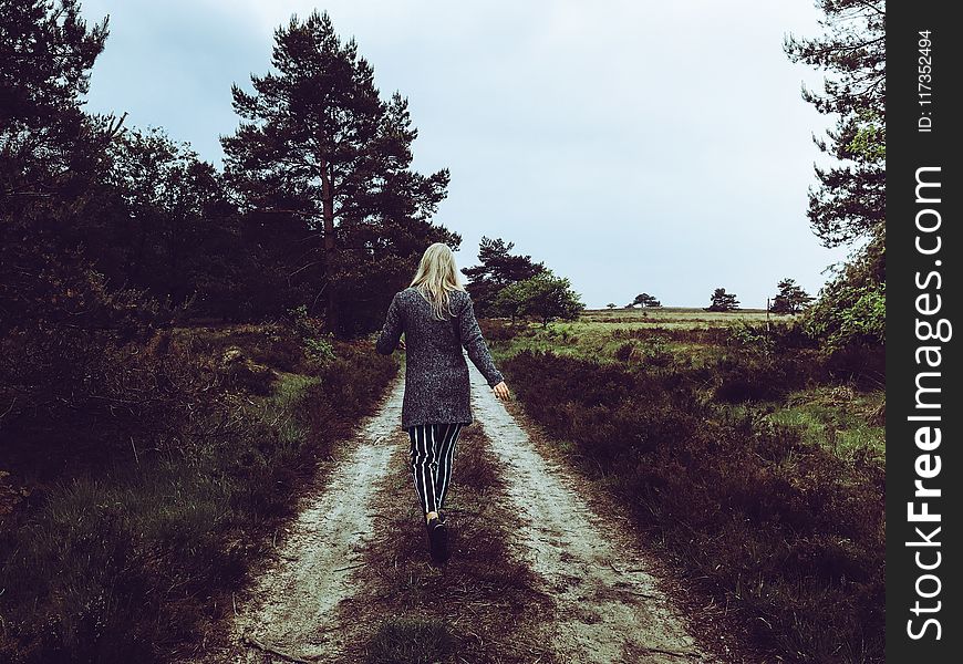 Woman In Grey Cardigan With Grey And Black Striped Pants Walking At The Pathway