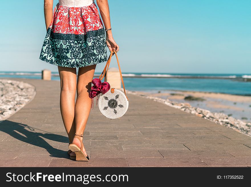 Woman Wearing Mini Skirt Holding Round Wicker Bag