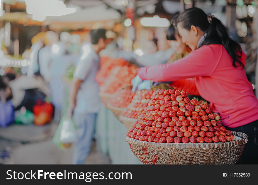 Selective Focus Photography Of Woman Wearing Red Hoodie Standing Behind Of Basket Full Of Fruits