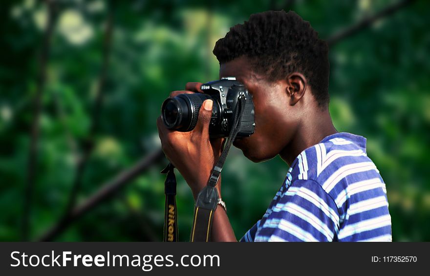 Man Wearing Blue And White Striped Shirt Using Nikon Camera