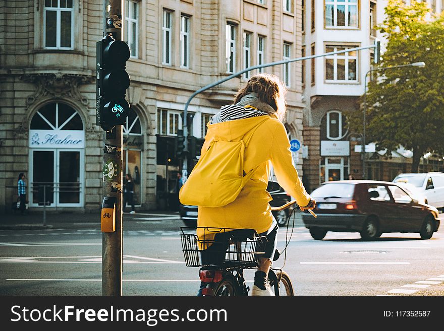 Woman Wearing Yellow Hooded Coat Riding Bicycle