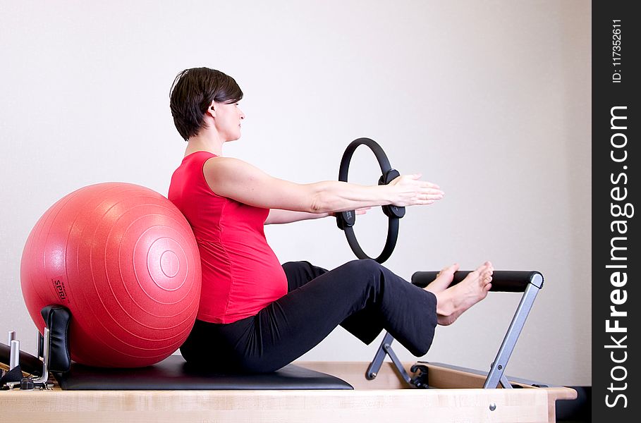 Woman in Red Shirt Sitting on Fitness Equipment