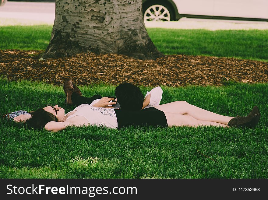 Woman Wearing White Tank Top Lying On Green Grass
