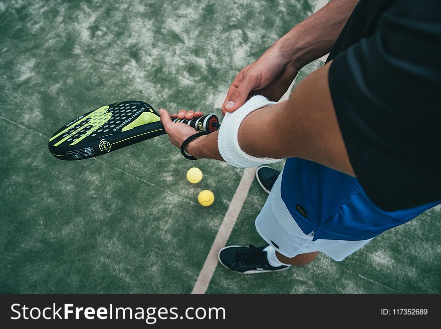 Person Holding Black and Green Tennis Racket