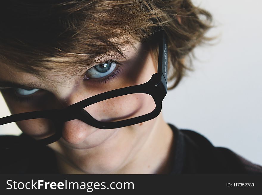 Woman in Black Top and Black Framed Eyeglasses Near White Wall