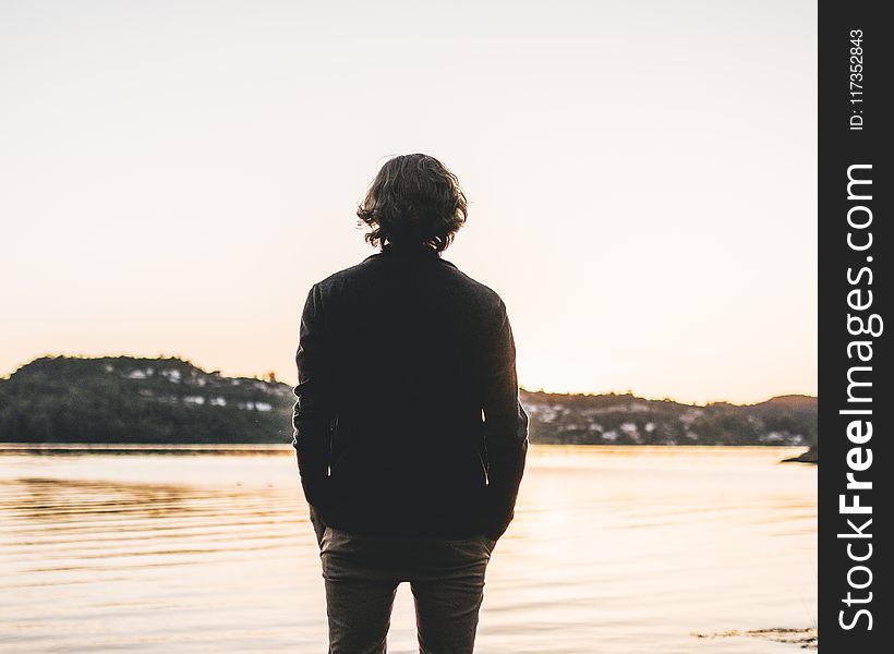 Man Standing Facing Body of Water