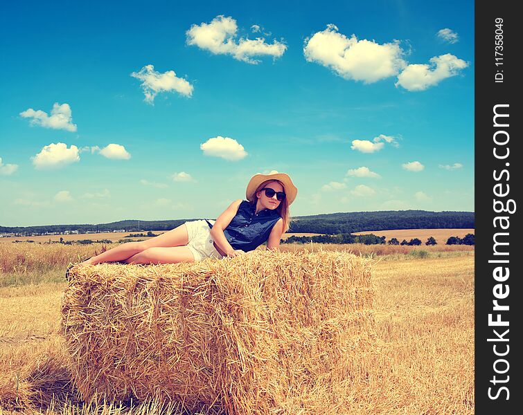 Woman lying on straw bale.