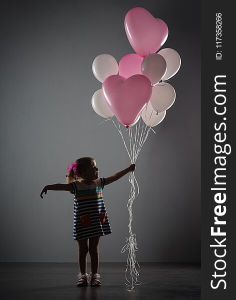 A girl four years old on a gray background with balloons. A girl four years old on a gray background with balloons