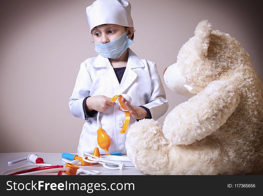 Cute little child girl playing doctor with teddy bear