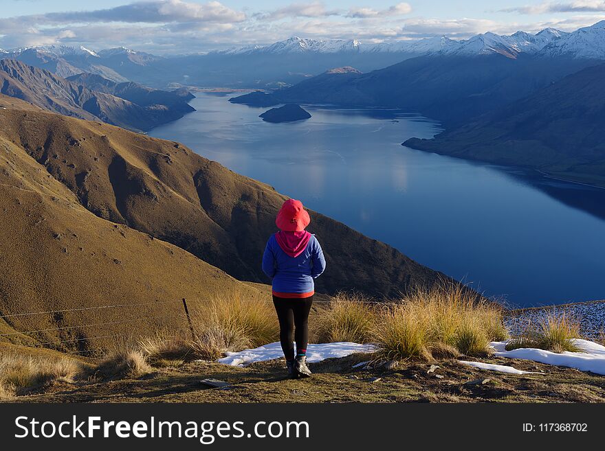 Lady hiker standing on top of the mountain - isthmus peak with a view of the Wanaka Lake