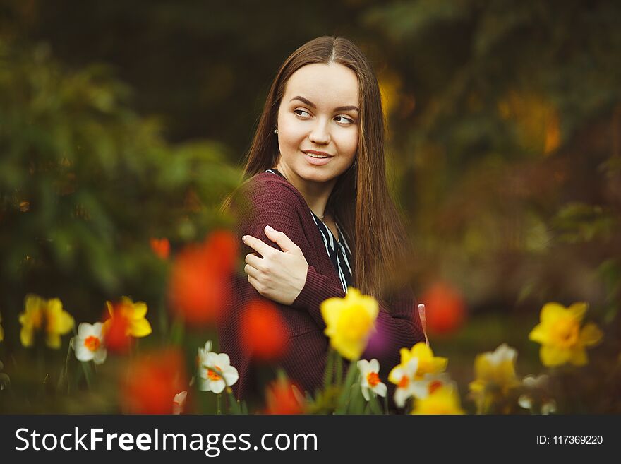 Beautiful girl sits at the planted flowers. portrait of cute woman on a background of seedlings.