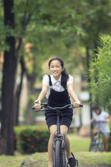 Toothy Smiling Face Of Asian Teenager Riding Bicycle In Green Pa Royalty Free Stock Image