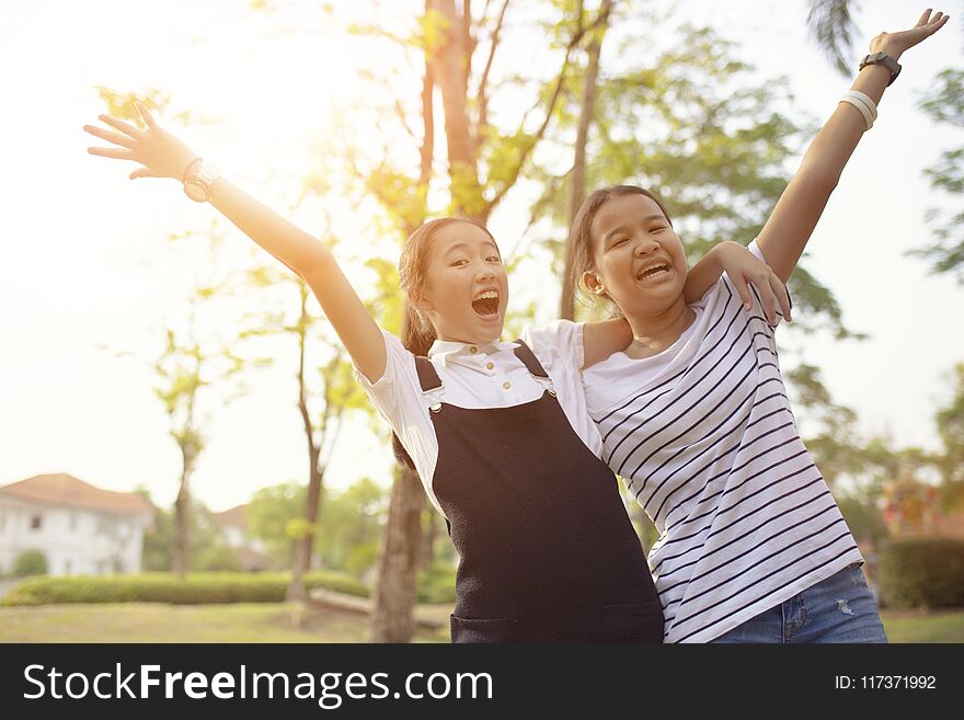 two asian teenager laughing with happiness emotion in green natural park