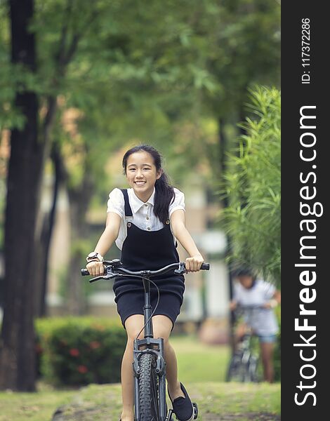 Toothy smiling face of asian teenager riding bicycle in green pa